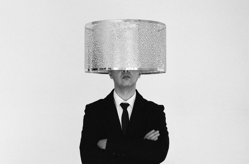 Portrait of man with strange hat standing against white background