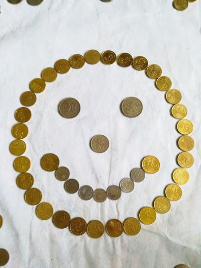 Close-up high angle view of coins resembling smiley emoticon. 