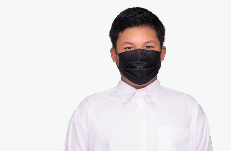 Portrait of young man standing against white background