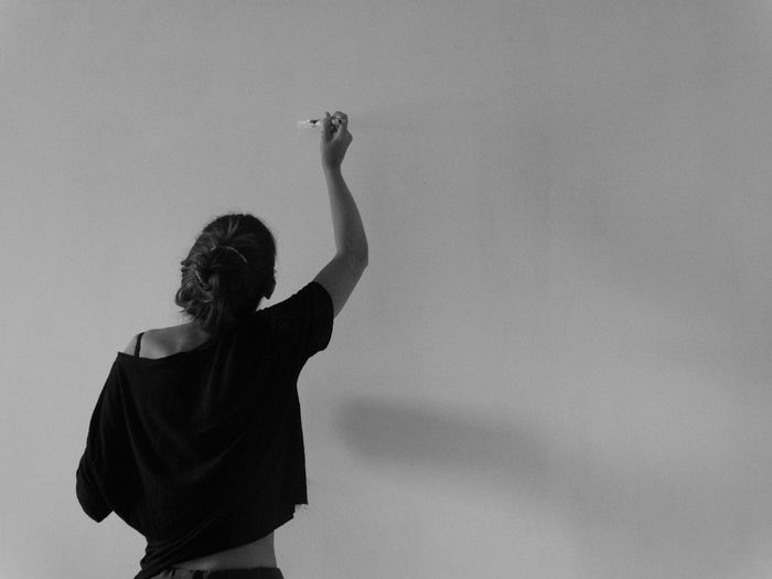 Rear view of woman painting on wall