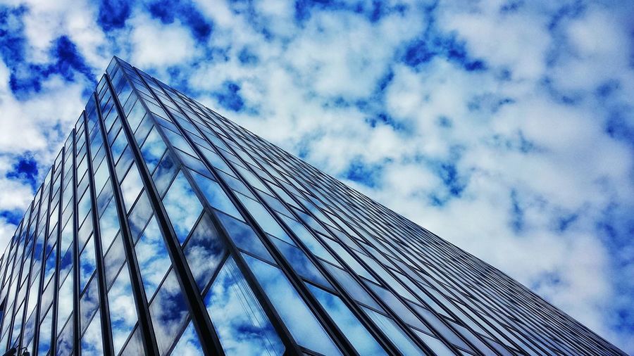 Low angle view of modern building against cloudy sky