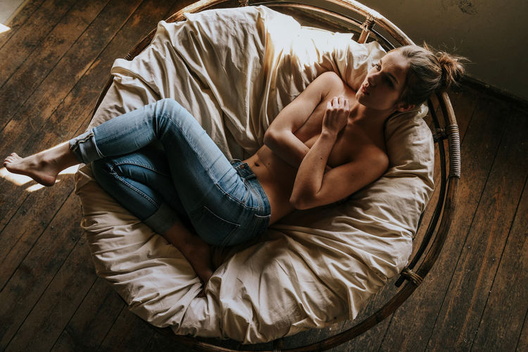 Directly above shot of shirtless woman lying on bed