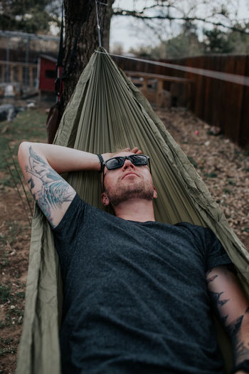 Vertical of man relaxing on hammock in backyard