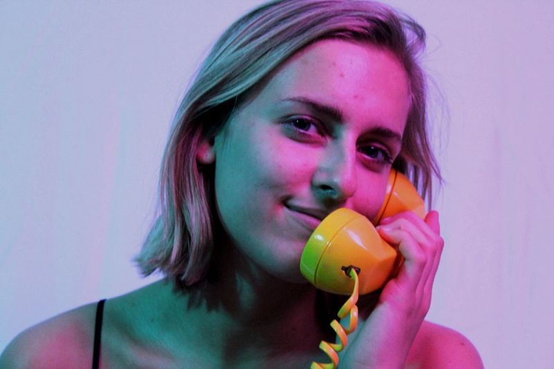 Portrait of smiling beautiful woman talking on yellow telephone