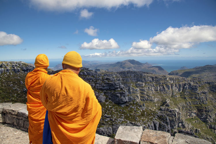 Rear view of monks standing against mountains