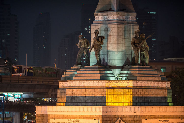 Soldier statues at illuminated victory monument in city