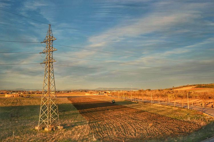 Electricity pylon on landscape against sky during sunset