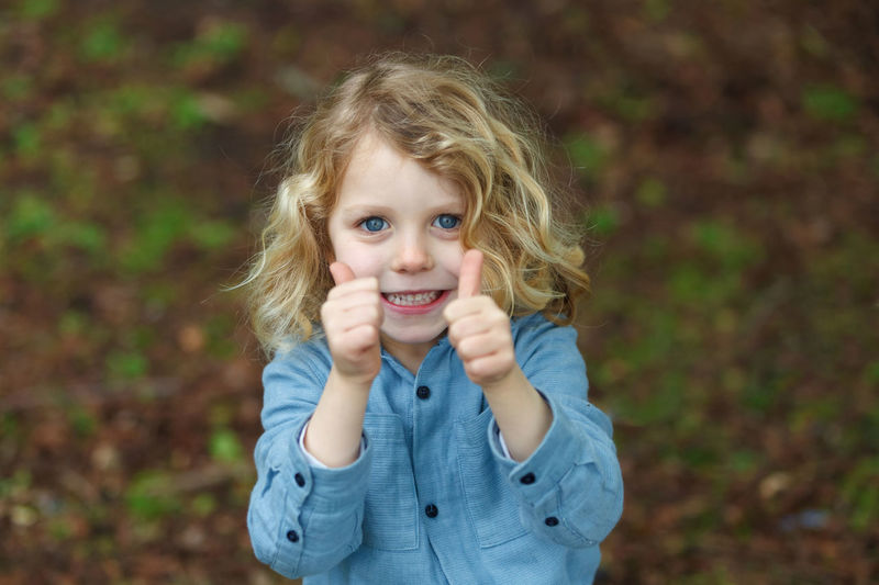 Portrait of cute girl showing thumbs up