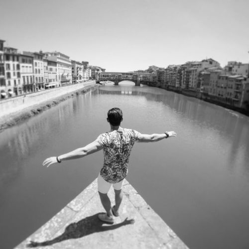 High angle view of man with arms outstretched standing by canal