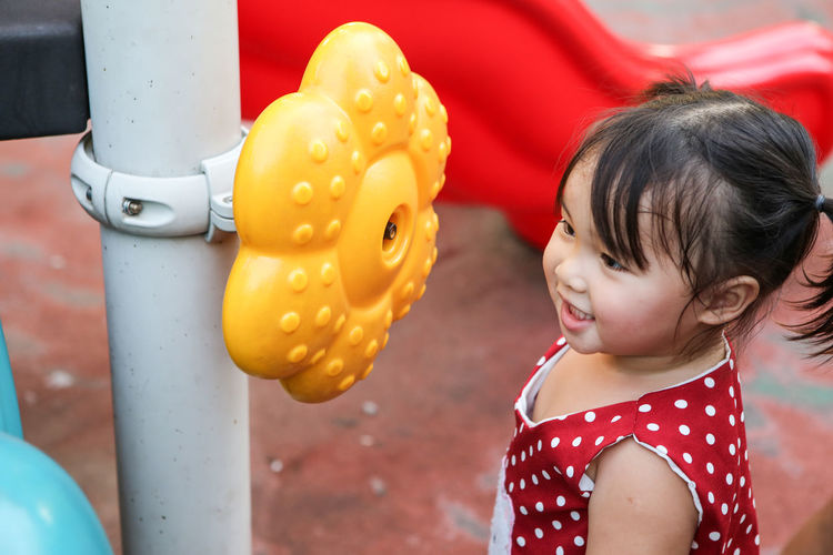Close-up of cute girl looking yellow toy garlands on the playground