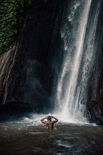 Man swimming by waterfall