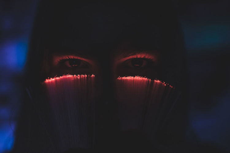 Close-up portrait of young woman in futuristic red lights under the eyes