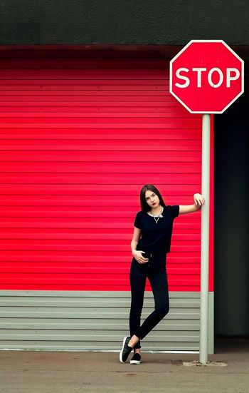 Full length of woman standing by stop sign