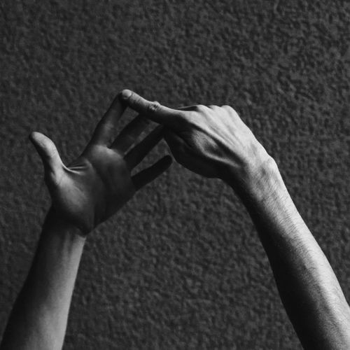 Cropped hands of man gesturing against wall