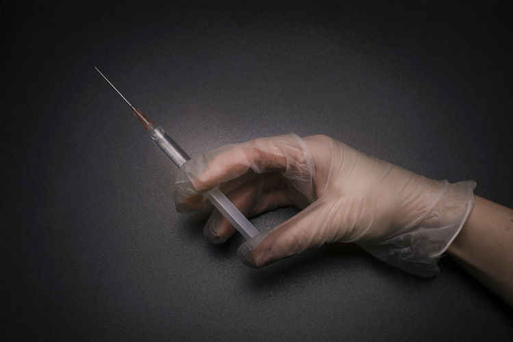 Hand with a syringe on the black background.