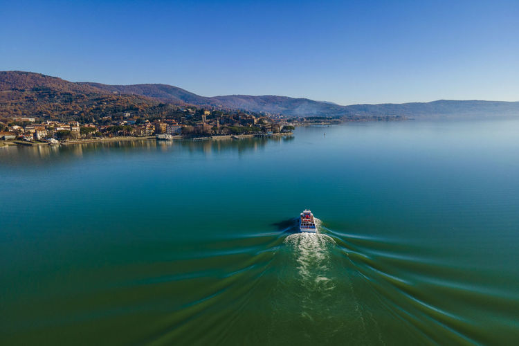 Aerial view of a sailing boat navigating on passignano sul trasimeno, a beautiful lake