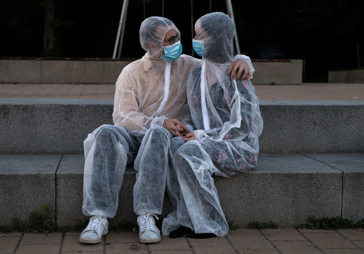 Communication in corona times. the young couple is very close despite the protective suits and masks