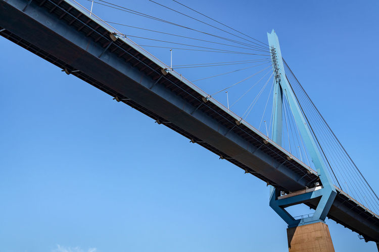 Low angle view of suspension bridge against clear blue sky