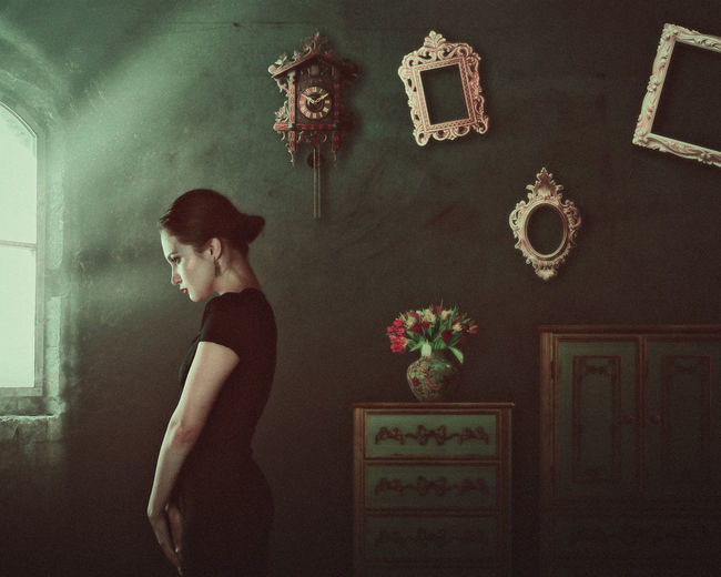 Side view of woman standing against wall at home