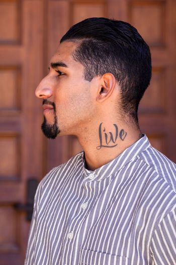 Man with live tattoo on neck at home