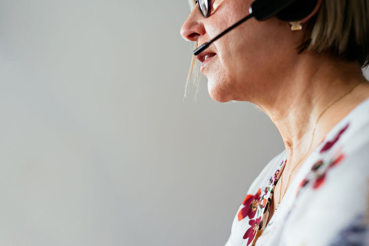Anonymous middle age female remote specialist in eyeglasses and headset working during telework at home