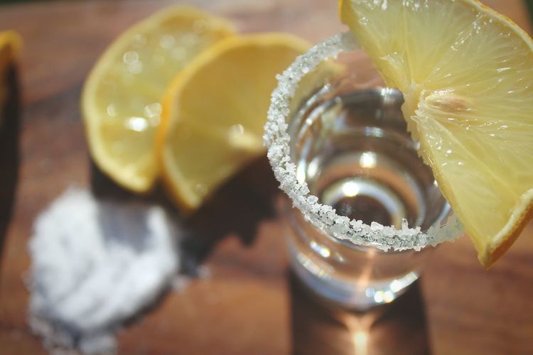 Close-up of tequila with lemons slices and salt served on table