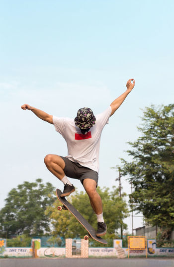 A young adult wearing a protective mask while doing an ollie stunt on his skateboard.