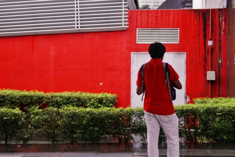 Rear view of man standing against red wall
