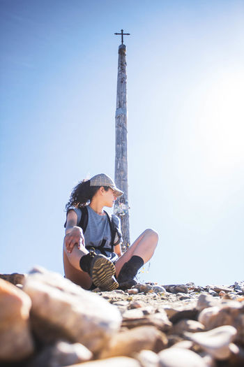 Woman sitting on stones against cross, making the road to santiago