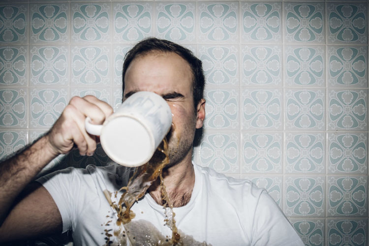 Man spilling coffee while drinking at home