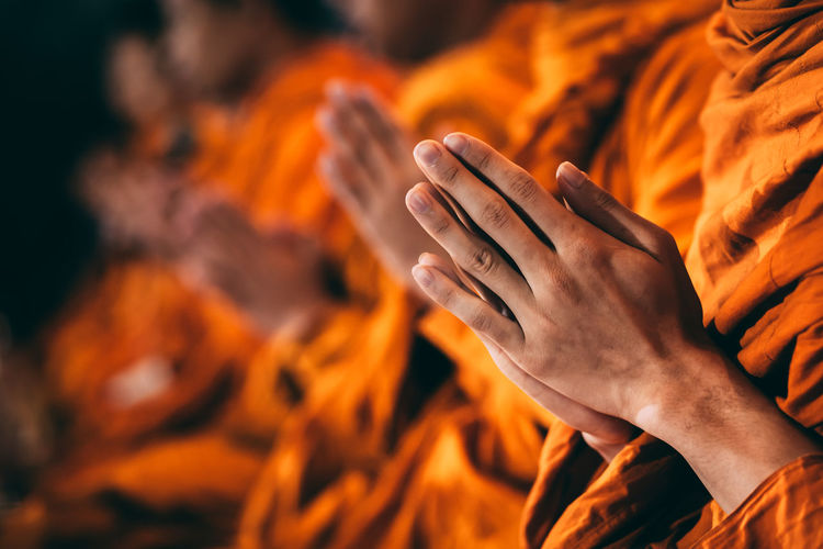 Midsection of monks with hands clasped