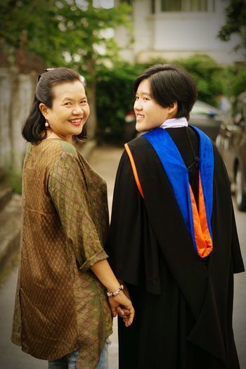 Rear view portrait of smiling woman with student on road