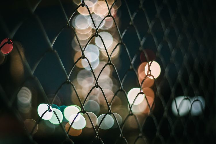 Chainlink fence against illuminated lighting equipment at night