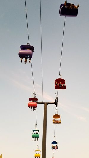 Low angle view of people sitting in ski lift against sky