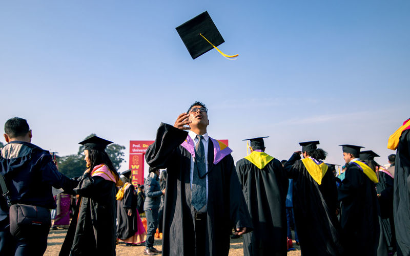 Man looking up while throwing mortarboard in sky
