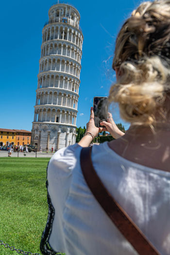 Woman photographing against leaning tower of pisa