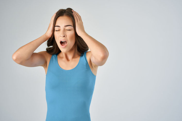 Frustrated woman shouting against gray background
