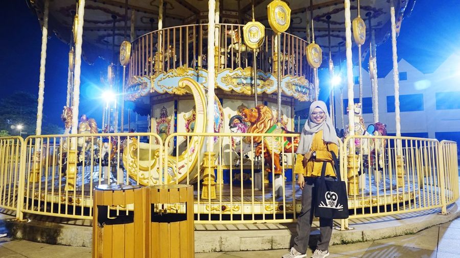 Woman standing in amusement park at night