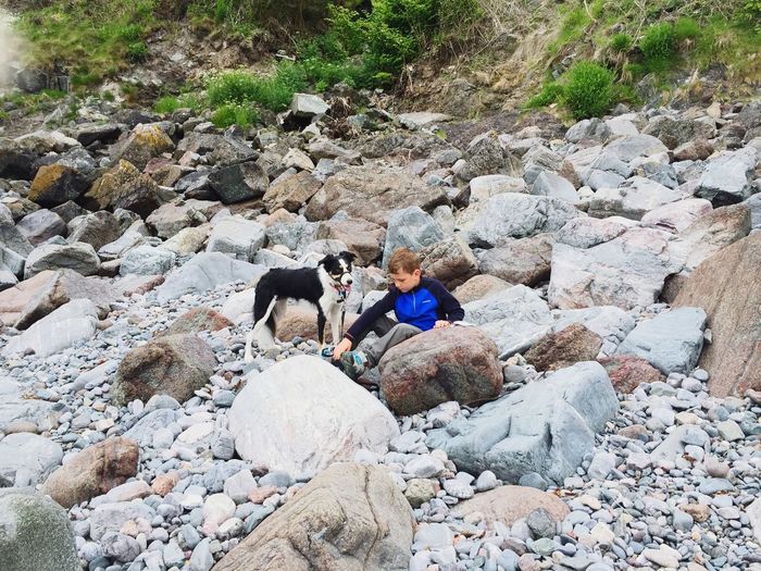 Boy with dog sitting on rocks