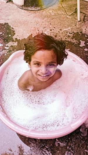 High angle portrait of girl bathing in tub at yard