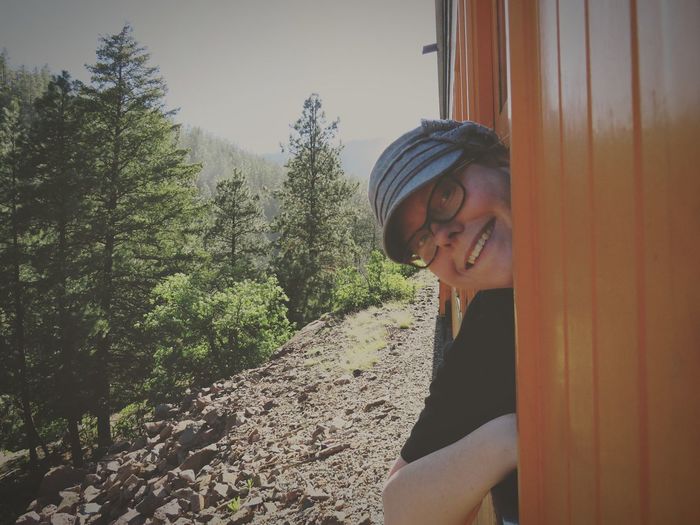Portrait of smiling woman peeking from train at forest