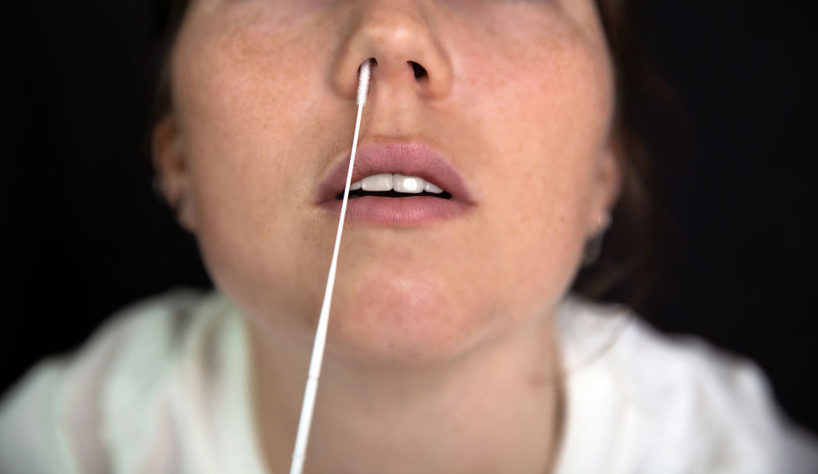 Close-up woman inserting cotton swab in nose