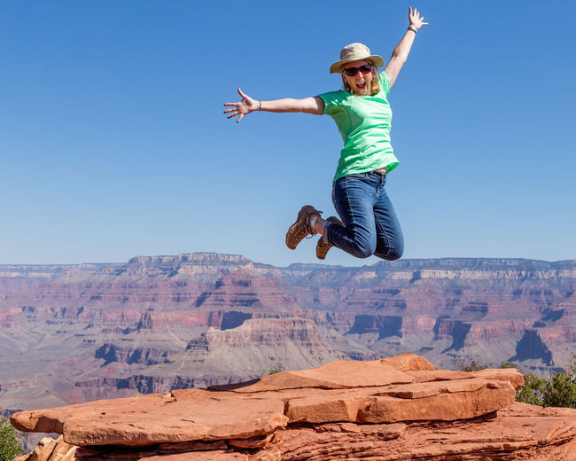 Full length of mature woman jumping against grand canyon