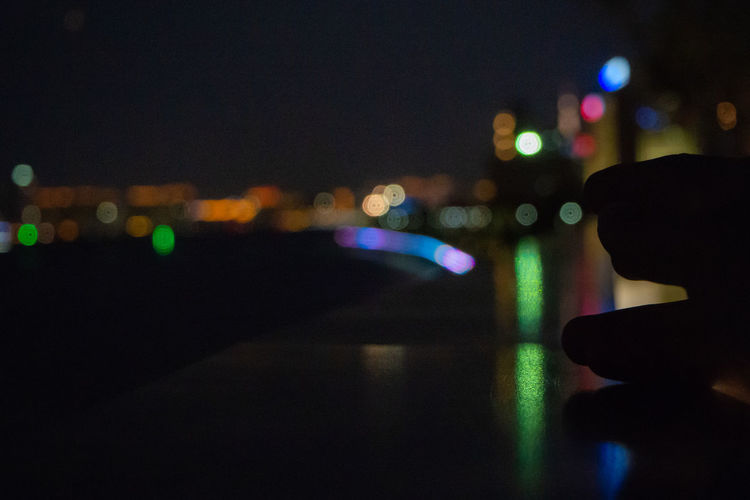 Close-up of hand on illuminated city at night