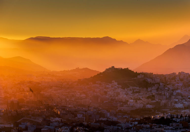 Townscape and mountain range against sky during sunset