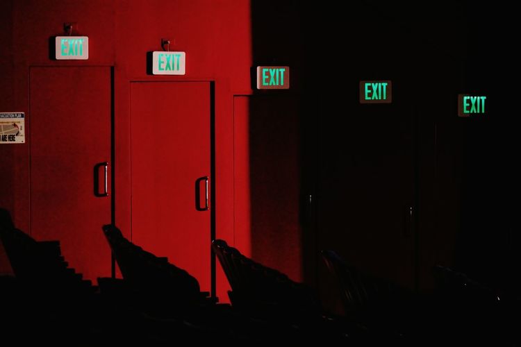 Exit signs on red wall at night