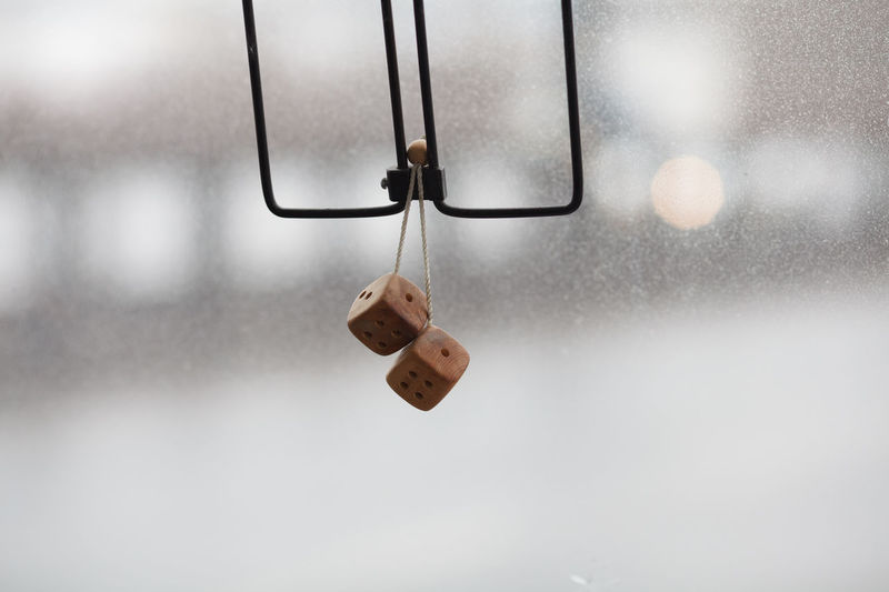 Close-up of dices hanging against dirty windshield in car