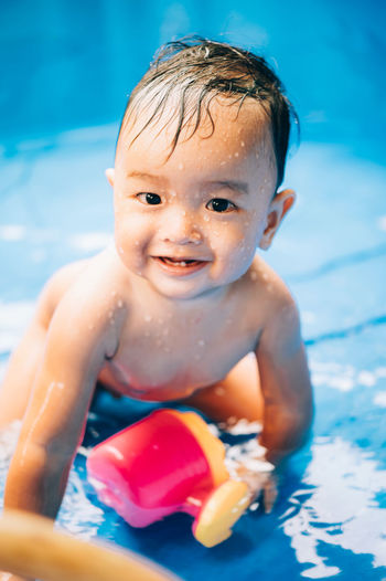 Close-up portrait of cute baby boy swimming in pool