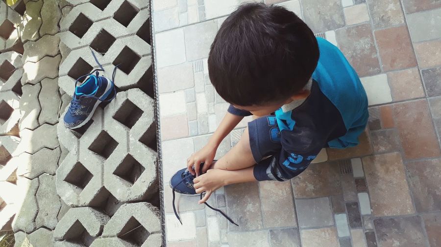 High angle view of boy tying shoelace at home