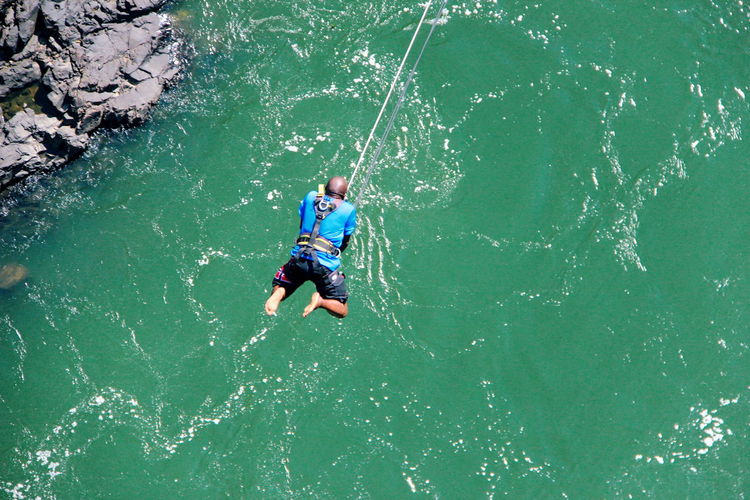 High angle view of man hanging on rope over river